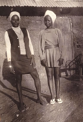 My Stylish Mother By Doris Rutere: My mother Cecilia Kanyoe was a copy typist at Marimanti Rural Training Centre back in 1975. She was always detailed and careful in her choice of office wear. In this photograph she is wearing closed toe heels and has broken her suit with a turtleneck that matches her head gear, a chain and a wrist watch. I think they present a level of sophistication making her refined and chic. Next to her is Esther Muthoni, who was my mother’s friend. In the picture, she wears a wide belt on her cute mini-dress to create contrast while matching her head gear partly with her shoes. Both women are quite careful in how they let their hands rest on their thighs./